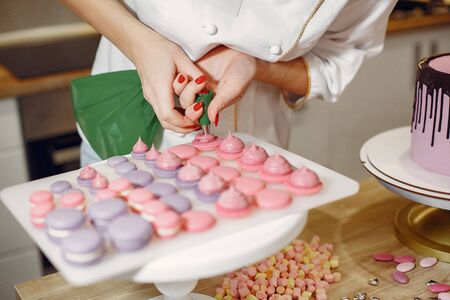Confectioner in a uniform decorates the macaroniの写真素材