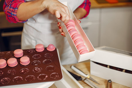 Confectioner in a uniform decorates the macaroni