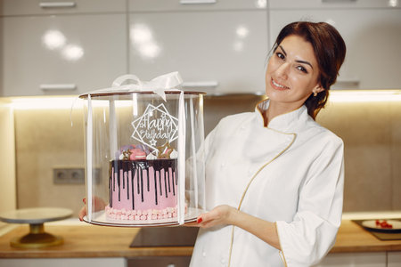 Confectioner in a uniform decorates the cake