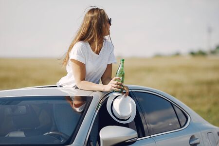 Elegant woman standing bin a hatch of the carの写真素材