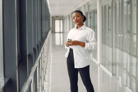 Black woman standing in the office with a laptopの写真素材