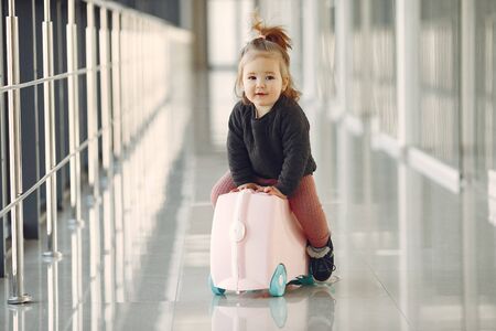 Little girl with a suitcase at the airportの写真素材