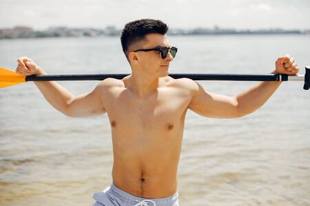 Handsome man with a sup. Surfer on a waterの写真素材