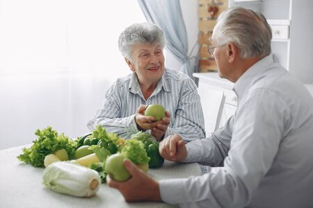 Beautiful old couple prepare food in a kitchenの写真素材