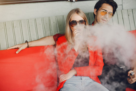 Stylish young couple with vape in a cityの写真素材