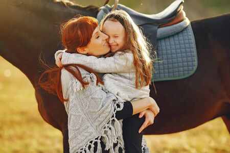 Mother and daughter in a field playing with a horseの写真素材