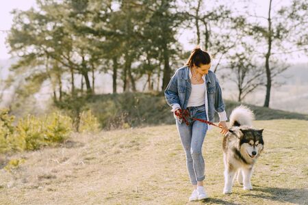 Stylish girl in a spring field with a dogの写真素材