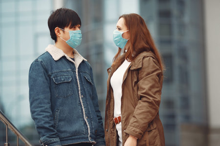 A woman and Chinese man are wearing protective masks