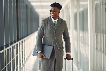 Elegant black man at the airport with a suitcaseの写真素材