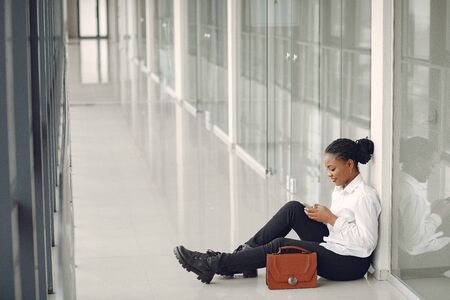 Black woman standing in the office with a laptopの写真素材