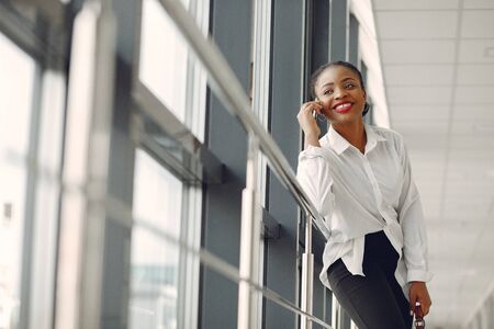 Black woman standing in the office with a laptopの写真素材