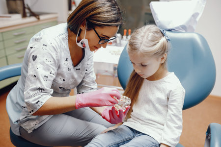 Cute little girl sitting in the dentists office