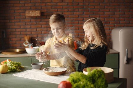Children playing with a flour in a kitchenの写真素材