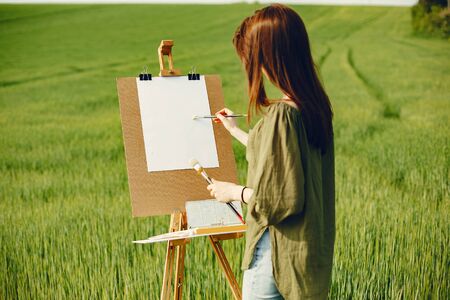 Elegant and beautiful girl painting in a fieldの写真素材