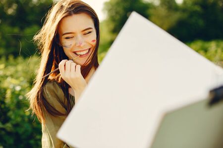 Elegant and beautiful girl painting in a fieldの写真素材