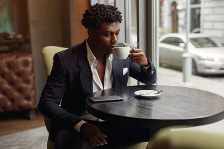 Black man sitting in a cafe and drinking a coffeeの写真素材