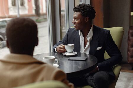 Black men sitting in a cafe and drinking a coffeeの写真素材