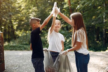 Children collects garbage in garbage bags in parkの写真素材