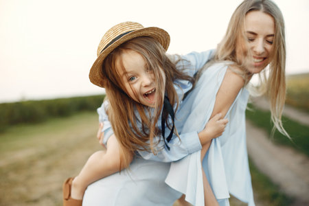 Mother with daughter playing in a summer fieldの写真素材