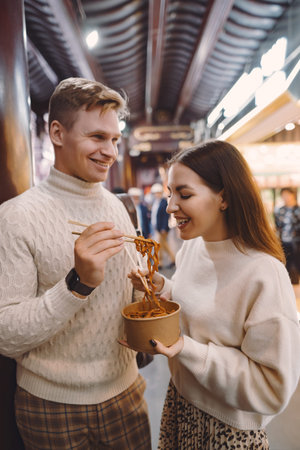 newlywed couple eating noodles with chopsticks in Shanghai outside a food market