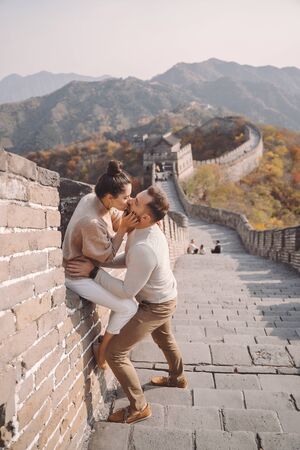 beautiful young couple sitting down and showing affection at the Great Wall of China.の写真素材