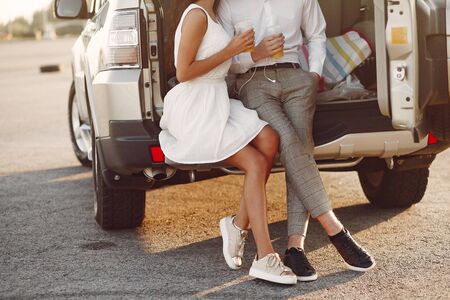 Beautiful couple spend time in a summer park near a carの写真素材