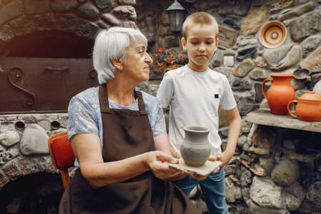 Grandmother with a grandchildren make pitchers in potteryの写真素材
