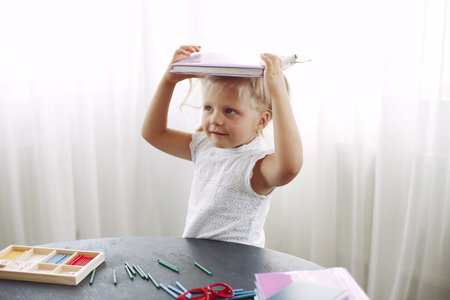 Little girl sitting on a table with books