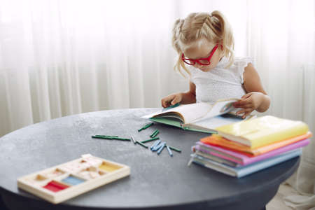 Little girl sitting on a table with booksの写真素材