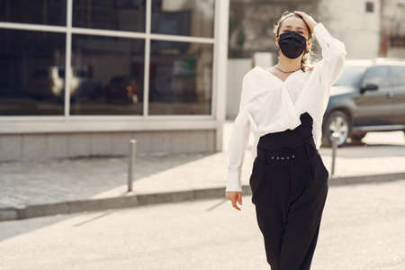 Woman in a mask stands on the streetの写真素材