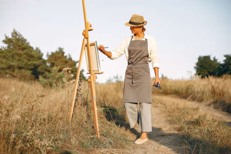 Woman in a apron painting in a fieldの写真素材