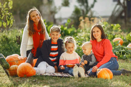 Big family sitting on a garden near many pumpkinsの写真素材