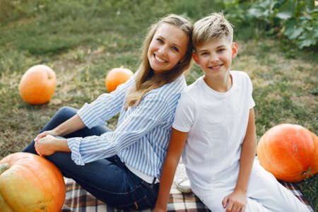 Mother and son sitting on a garden near many pumpkinsの写真素材