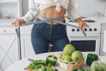 Beautiful and sporty girl in a kitchen with a vegetablesの写真素材