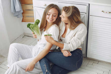 Beautiful and sporty girls in a kitchen with a vegetablesの写真素材