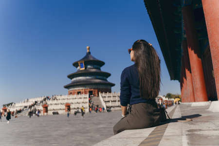 brunette girl sitting on the steps by temple of heven in Chinaの写真素材