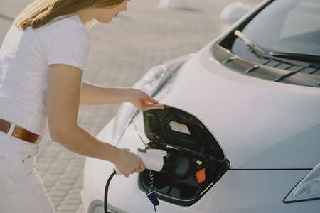 Woman charging electro car at the electric gas stationの写真素材