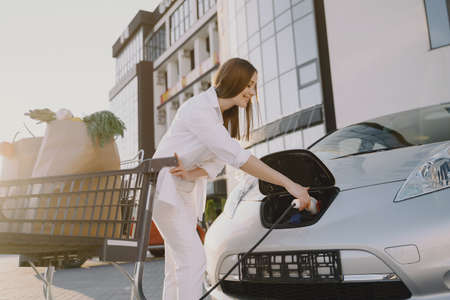 Woman charging electro car at the electric gas stationの写真素材