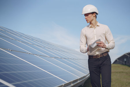Businessman in a white helmet near solar battery