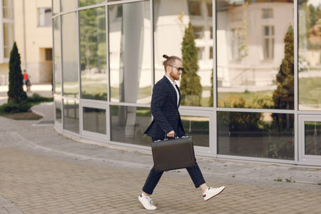 Businessman with suitcase walking in a summer city