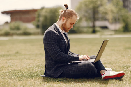 Businessman with laptop in a summer city