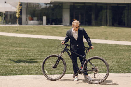 Businessman with bicycle in a summer cityの写真素材
