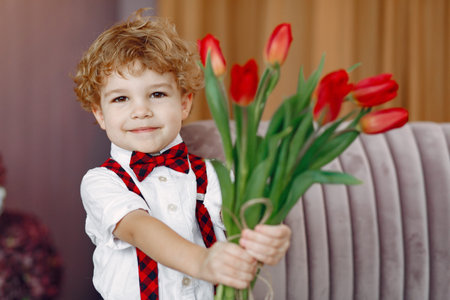 Elegant little boy in a studio with bouquet of tulip
