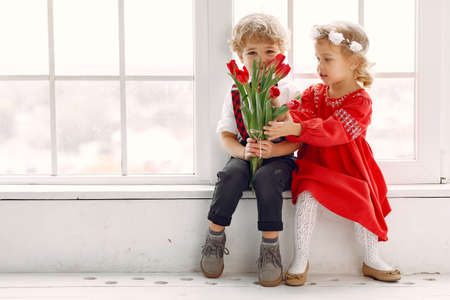 Elegant little kids in a studio with bouquet of tulipの写真素材