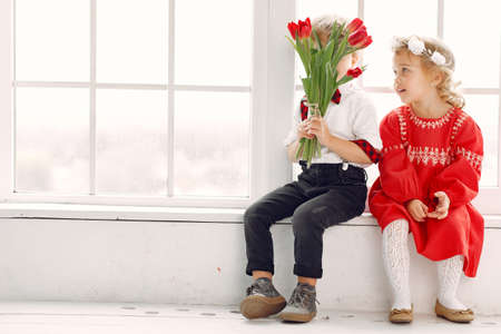 Elegant little kids in a studio with bouquet of tulipの写真素材