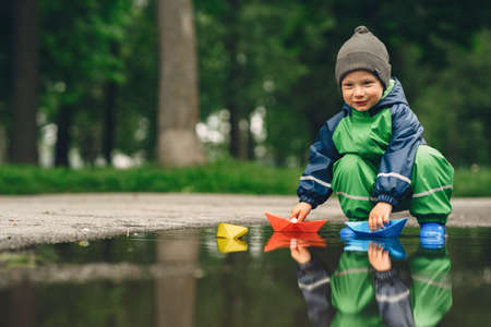 Funny kid in rain boots playing in a rain parkの写真素材