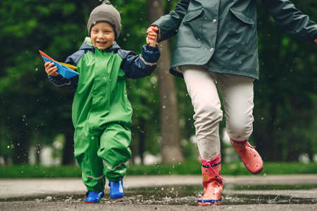 Funny kid in rain boots playing in a rain parkの写真素材