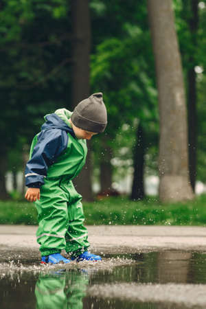 Funny kid in rain boots playing in a rain parkの写真素材