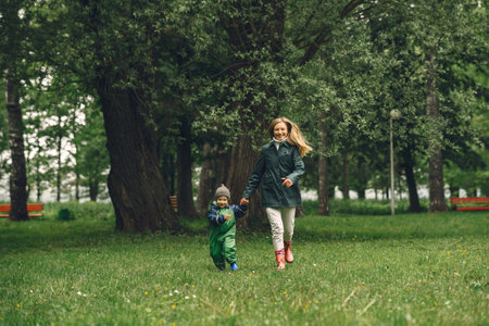 Funny kid in rain boots playing in a rain park