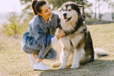 Stylish girl in a spring field with a dogの写真素材